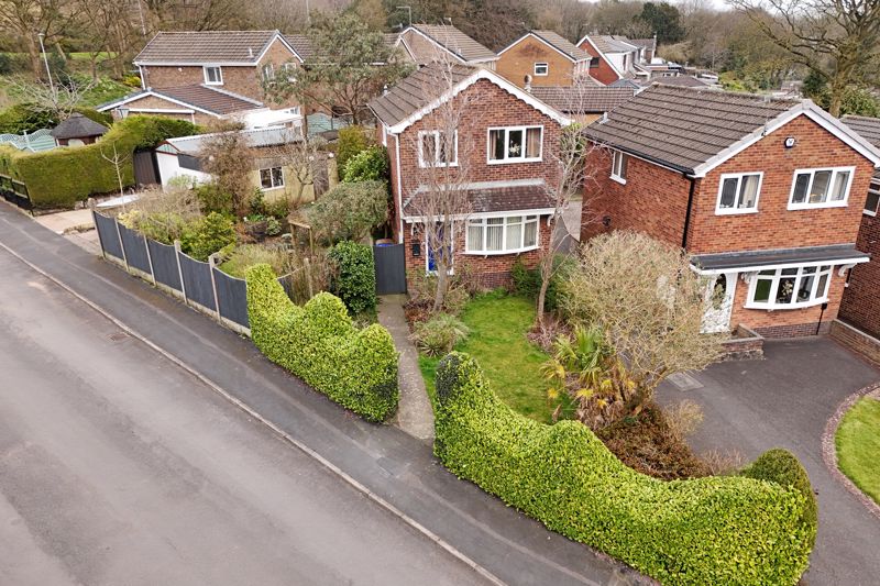 Aerial photography of a home front elevation, hedges and roadside in the foreground.