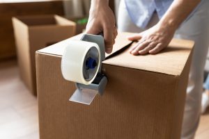 Close up of a person closing a box with tape.