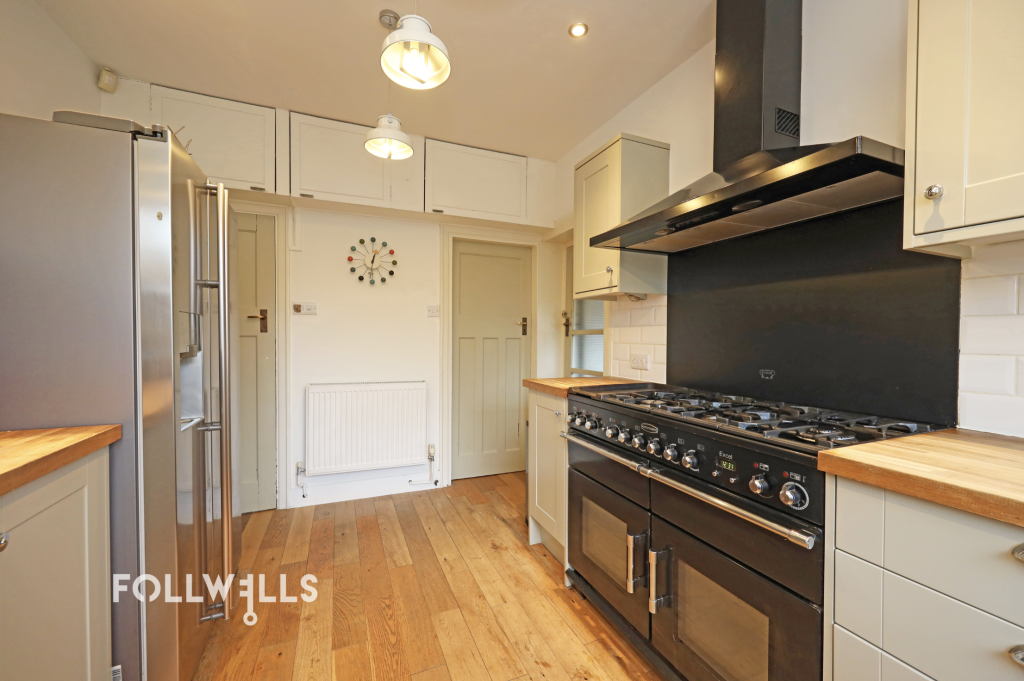 Modern kitchen with range cooker, wooden worktops, light cabinetry and hardwood flooring.
