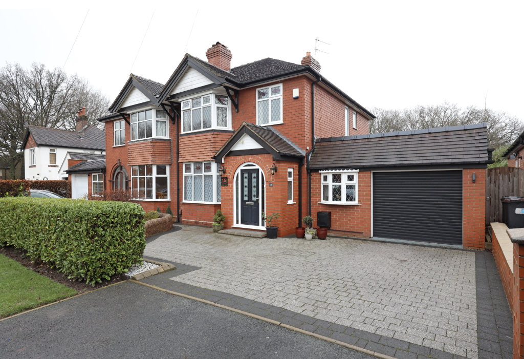 Detached red brick home with bay windows, driveway parking and integrated garage in a quiet residential area.